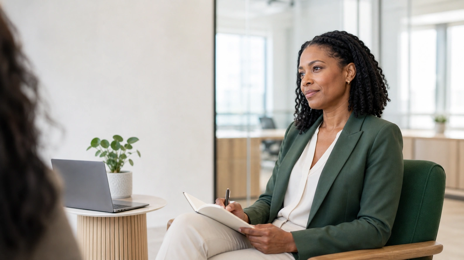 A poised candidate seated calmly in a bright modern interview room, notebook in hand, composed rather than nervous mid-conversation